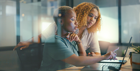 deux jeunes femmes travaillant ensemble sur un ordinateur portable.