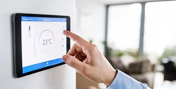 Une personne ajuste la température d'un thermostat connecté 