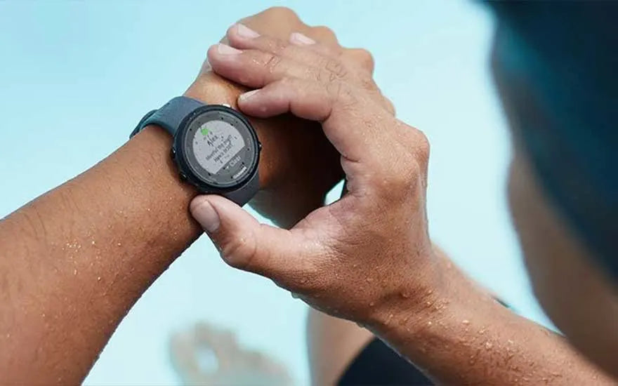 Une personne consulte une notification sur sa montre connectée après une activité sportive en piscine.