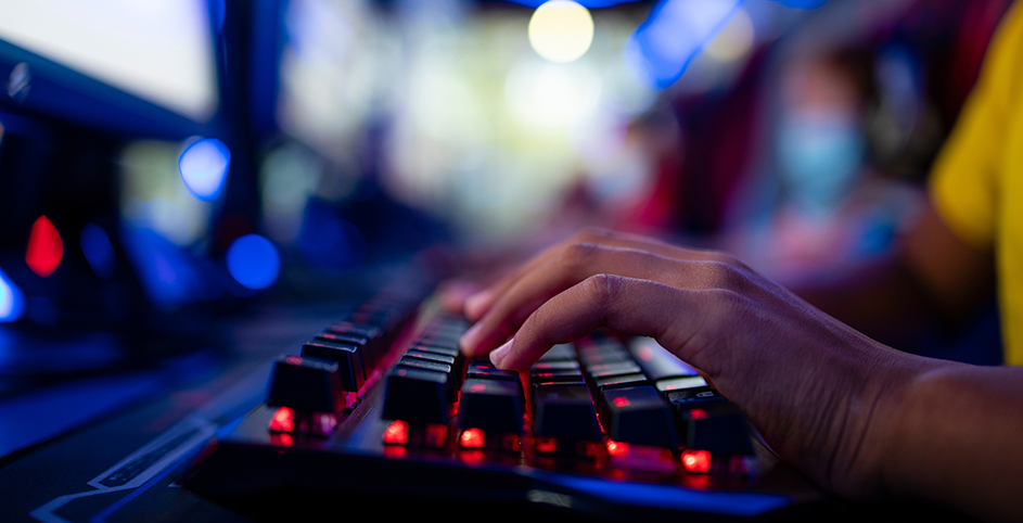 Une personne utilisé un clavier gaming rétroéclairé dans une salle colorée.