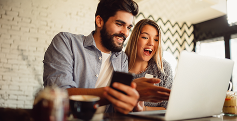 Un couple utilisant un ordinateur portable tout en consultant un smartphone.