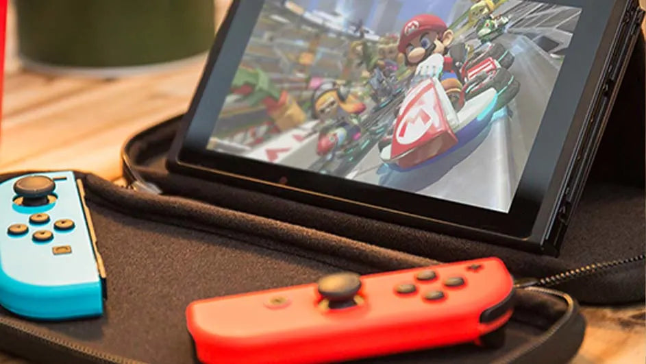 Une Nintendo Switch en mode sur table, affichant Mario Kart, avec des Joy-Con rouge et bleu posés dans une housse.
