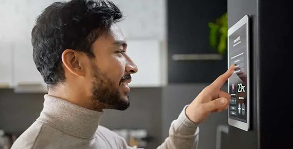 Un homme qui effectue des réglages sur un thermostat connecté tactile.