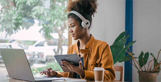 jeune femme avec casque sur les oreilles qui travaillent sur son ordinateur portable et sa tablette.