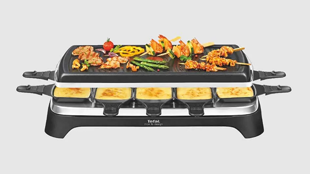 Un appareil à raclette Tefal garni de légumes, viande, brochette et poêlons de fromage fondu.