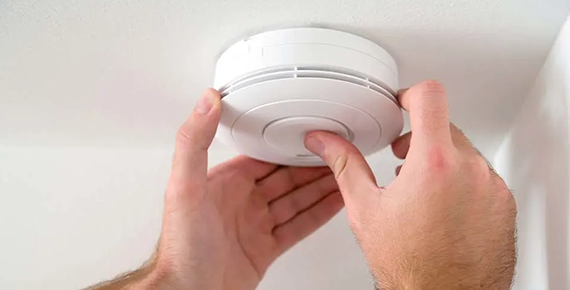 Installation d'un détecteur de fumée au plafond.