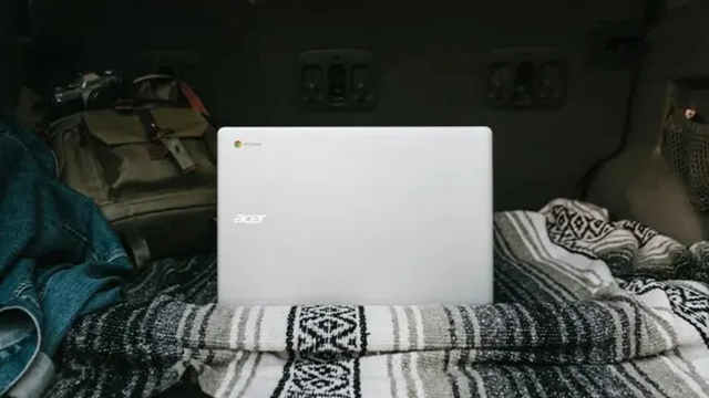 Un pc portable ouvert posé sur une couverture.