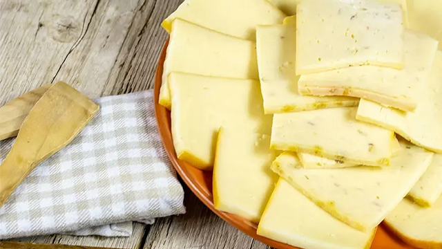 Une assiette de fromage à raclette sur une table en bois.