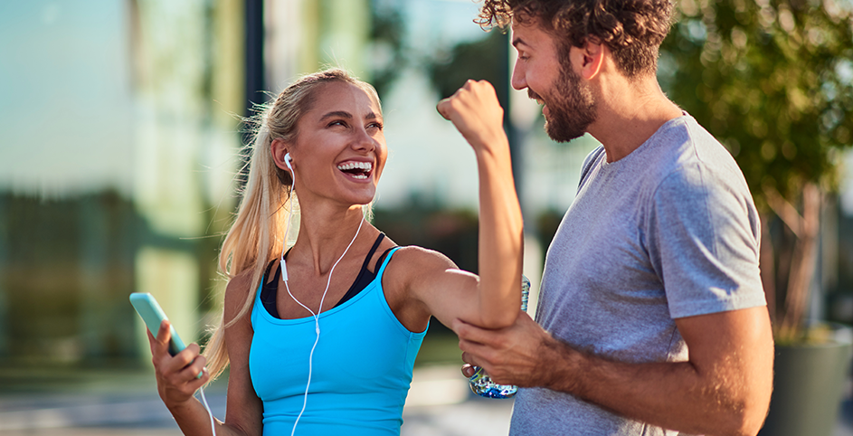 Une femme et un homme discutent en souriant après une séance de sport.