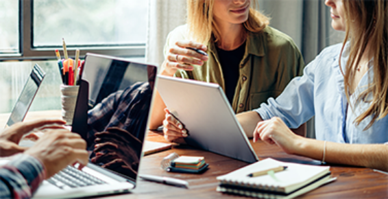 trois personnes assis autour d'une table travaillant sur leurs ordinateurs portables.