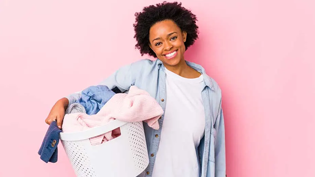 Jeune femme tenant un bac à linge dans les mains.