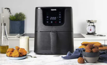 Un airfryer vu de face posé sur une table de cuisine.