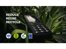 Charger l&#39;image dans la galerie, Un téléphone portable noir avec un clavier, couché parmi des plantes vertes, avec le texte: &#39;REDUCE REUSE RECYCLE&#39;.
