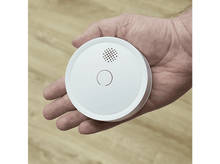 Charger l&#39;image dans la galerie, Une main tenant un détecteur de fumée blanc. L&#39;appareil a un design circulaire.
