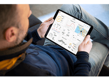 Charger l&#39;image dans la galerie, Un homme tient une tablette, regardant une application météo avec des graphiques et une carte. Il porte une veste.
