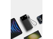 Charger l&#39;image dans la galerie, Batterie externe noire avec écran et câble USB, plus deux smartphones. Un en charge, un avec des lignes néon.
