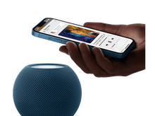 Charger l&#39;image dans la galerie, Personne tenant un téléphone bleu avec une application de musique ouverte à côté d&#39;un HomePod bleu.
