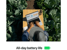 Charger l&#39;image dans la galerie, Personne utilisant un ordinateur portable à l&#39;extérieur sur une table en bois, entourée de cultures.
