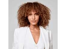 Charger l&#39;image dans la galerie, Une femme aux cheveux bruns bouclés, portant un blazer blanc, regardant la caméra.
