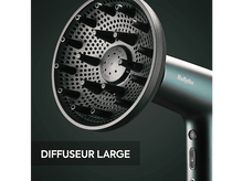 Charger l&#39;image dans la galerie, Un diffuseur noir pour un sèche-cheveux. Le diffuseur est grand et comporte de nombreux trous. Un sèche-cheveux Babyliss en arrière-plan.
