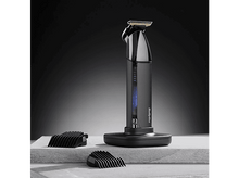 Charger l&#39;image dans la galerie, Tondeuse à cheveux noire et argentée avec accessoires, sur une surface en pierre.
