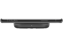 Charger l&#39;image dans la galerie, Un chargeur sans fil noir avec un téléphone dessus, vue latérale, sur fond blanc.
