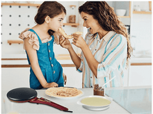 Charger l&#39;image dans la galerie, Femme et fille mangeant des crêpes, crêpière, ingrédients sur la table.
