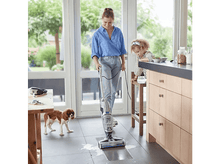 Charger l&#39;image dans la galerie, Une femme passe l&#39;aspirateur sur une zone humide du sol avec un enfant et un chien.
