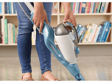 Charger l&#39;image dans la galerie, Personne utilisant un balai vapeur bleu et blanc sur un sol, avec une bibliothèque en arrière-plan.
