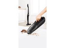 Charger l&#39;image dans la galerie, Un aspirateur à main noir utilisé pour nettoyer les miettes d&#39;une surface blanche. Un autre aspirateur se trouve derrière.
