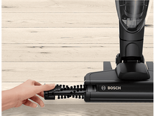 Charger l&#39;image dans la galerie, Main tenant une tête de brosse d&#39;aspirateur, sur fond en bois.
