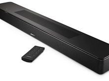 Charger l&#39;image dans la galerie, Barre de son Bose noire avec une télécommande. La barre de son est sur une surface blanche.
