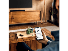 Charger l&#39;image dans la galerie, Une personne tenant un smartphone avec une interface de contrôle. Montre une barre de son, sur une table.
