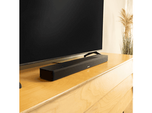 Charger l&#39;image dans la galerie, Une barre de son noire sur une commode en bois sous une grande télévision noire.
