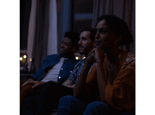 Charger l&#39;image dans la galerie, Trois personnes regardant quelque chose sur un écran dans une pièce sombre, éclairées par quelques lumières à l&#39;arrière-plan.
