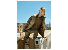 Charger l&#39;image dans la galerie, Un homme portant un casque et un gilet est assis sur un conteneur. Le fond est un ciel bleu clair.
