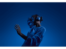 Charger l&#39;image dans la galerie, Femme en chemise bleue avec casque. Tête inclinée en arrière, mains près de la tête.
