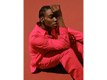 Charger l&#39;image dans la galerie, Homme en costume rouge avec écouteurs, main sur le visage, fond rouge.
