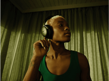 Charger l&#39;image dans la galerie, Une personne portant un casque noir, regardant ailleurs, avec un fond vert et un tatouage.
