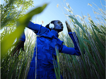 Charger l&#39;image dans la galerie, Un homme en tenue bleue avec un casque court à travers les hautes herbes.
