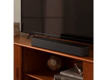 Charger l&#39;image dans la galerie, Barre de son noire sur un meuble en bois sous une TV.
