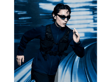 Charger l&#39;image dans la galerie, Homme courant avec des lunettes de soleil et un gilet, fond bleu, mouvement.
