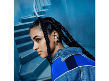 Charger l&#39;image dans la galerie, Une femme portant un écouteur noir et blanc, avec des tresses et une veste bleue.
