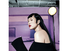 Charger l&#39;image dans la galerie, Femme asiatique en tenue noire et boucles d&#39;oreilles, rouge à lèvres rouge, regardant sur le côté. Studio.
