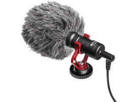 Un microphone noir avec une bonnette en fourrure et des accents rouges, sur fond noir.