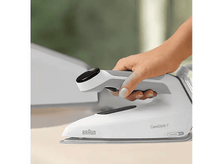 Charger l&#39;image dans la galerie, Un fer à repasser blanc avec une poignée grise est tenu par une main. Un autre fer en arrière-plan.
