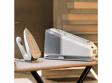 Charger l&#39;image dans la galerie, Station de repassage avec un fer à repasser et un générateur de vapeur sur une planche à repasser blanche. Le fer est sur son support.
