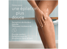 Charger l&#39;image dans la galerie, Femme s&#39;épilant la jambe sous la douche, eau et texte à gauche.
