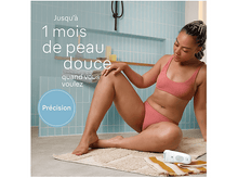 Charger l&#39;image dans la galerie, Femme dans la salle de bain, rasant ses jambes avec une épilateur. Épilateur blanc sur tapis beige, carreaux bleus.
