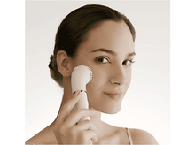 Charger l&#39;image dans la galerie, Femme utilisant une brosse nettoyante faciale blanche sur sa joue, souriant sur fond clair.
